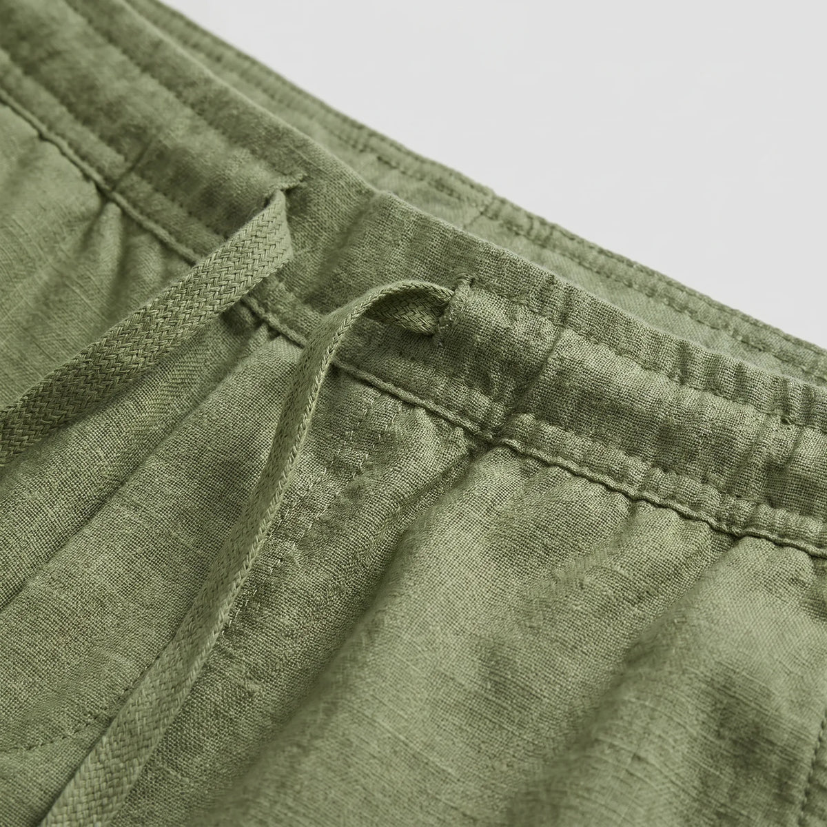 Close-up of the waistband and fly detail on navy blue linen shorts
