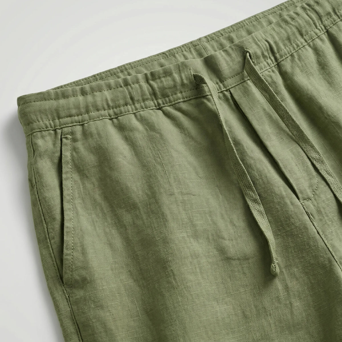 Black linen shorts laid flat, showing the elasticated waist and drawstring