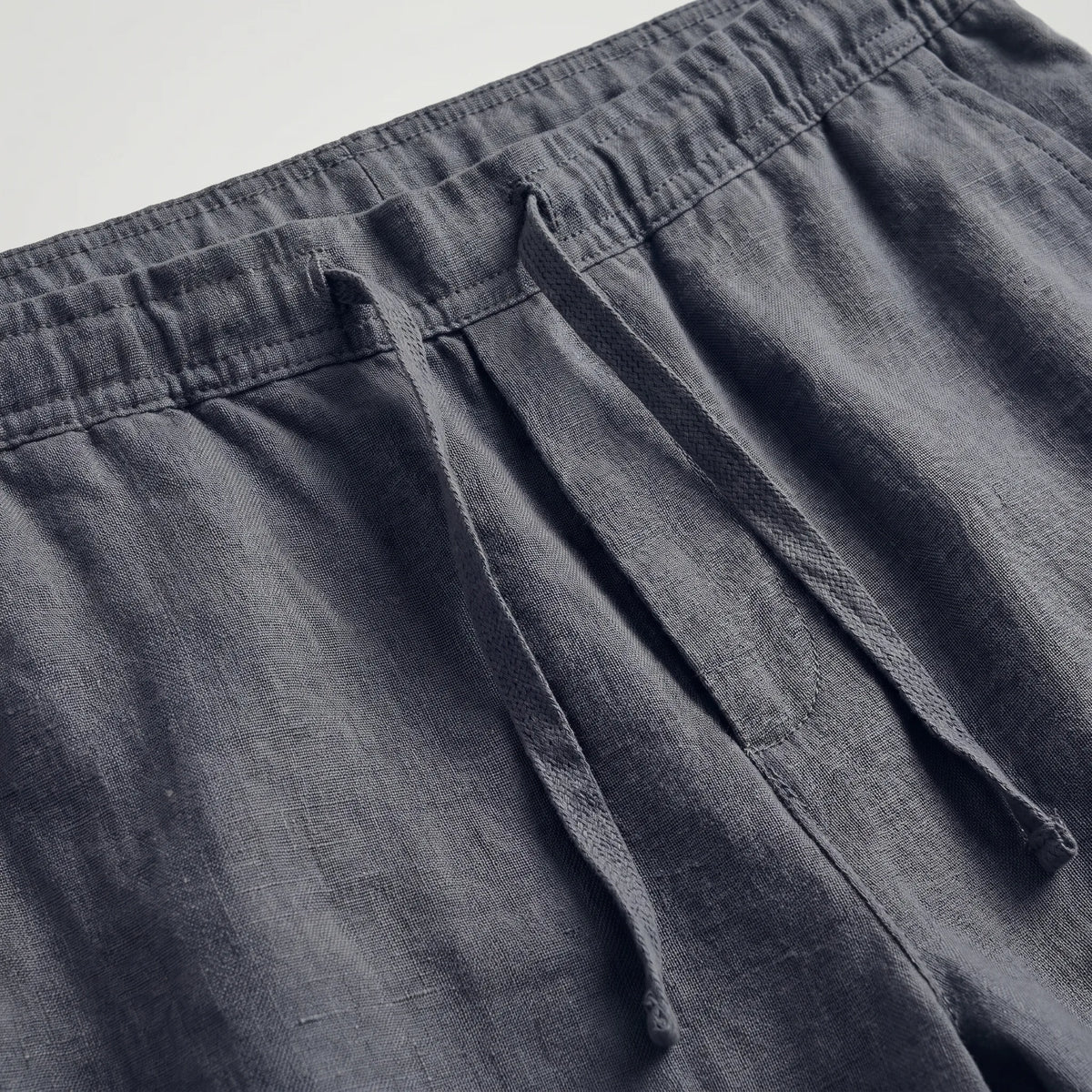 Green linen shorts laid flat, highlighting the relaxed above-knee length