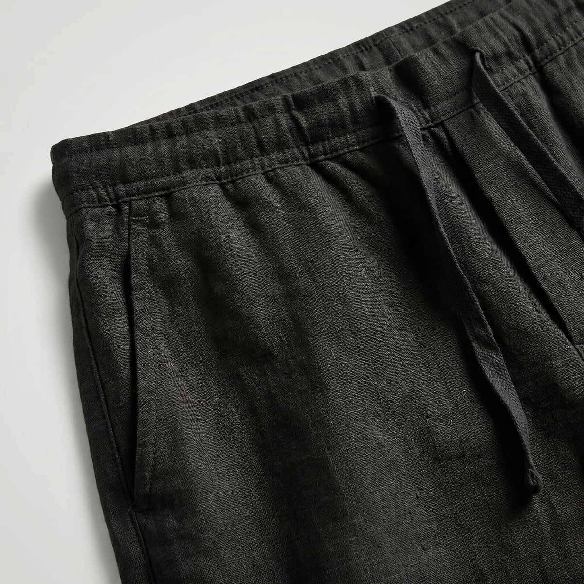 Grey linen shorts shown from a slight angle, highlighting the fabric drape