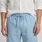 Close-up of the drawstring tie and elasticated waistband on light blue linen shorts