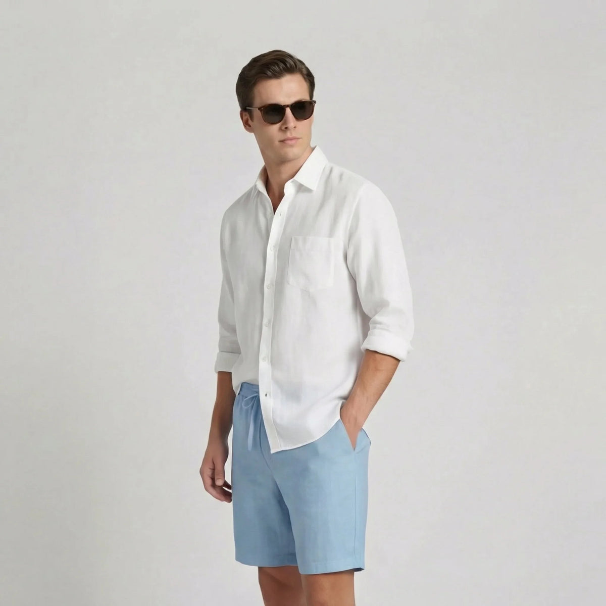 Side profile of a man wearing light blue linen shorts paired with a white linen shirt and sunglasses