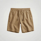 Khaki linen shorts laid flat, showing the relaxed fit and tapered hem