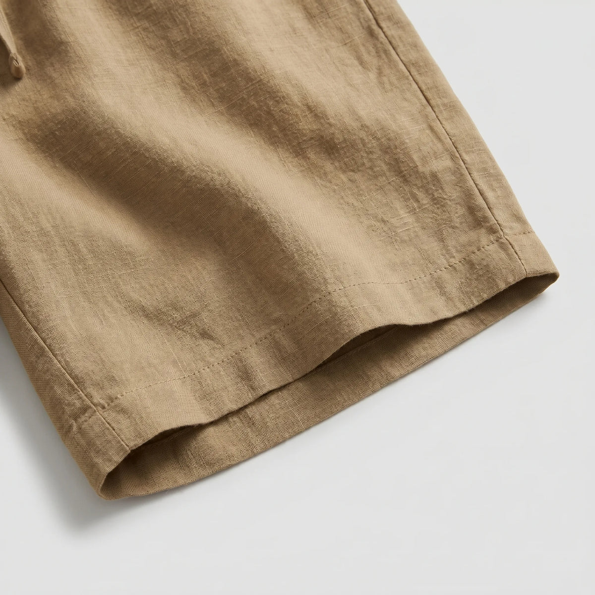Close-up of the hem and woven linen texture on khaki shorts