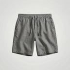 Grey linen shorts laid flat, displaying the drawstring waistband and slanted side pockets