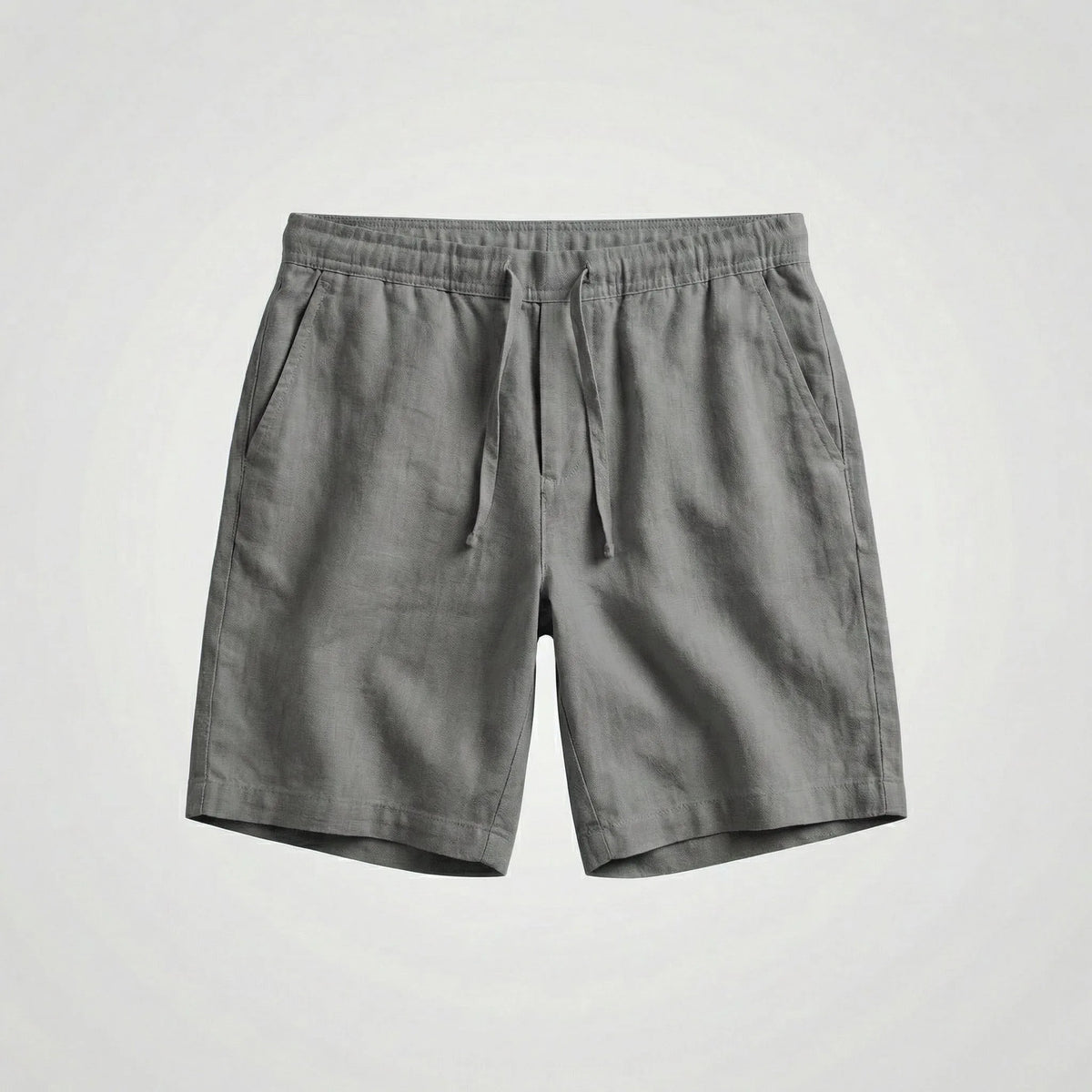 Grey linen shorts laid flat, displaying the drawstring waistband and slanted side pockets