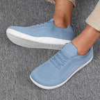 Close-up side view of light blue knit sneaker worn on foot, white sole, ribbed texture visible