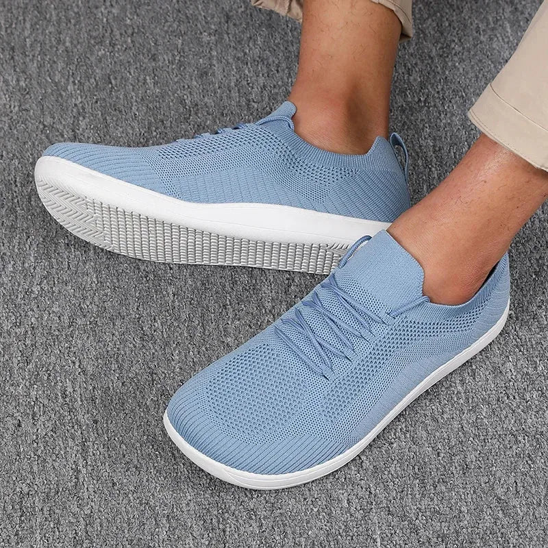 Close-up side view of light blue knit sneaker worn on foot, white sole, ribbed texture visible