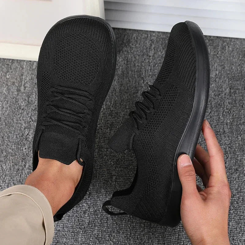 Front angle of light blue sneaker on foot beside bare foot, white sole visible