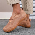 Wide shot of light blue sneakers worn with rolled beige trousers on textured grey carpet