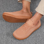 Close-up of orange knit sneaker with matching gum sole, worn on foot against carpet