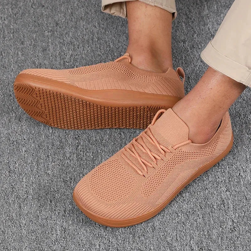 Close-up of orange knit sneaker with matching gum sole, worn on foot against carpet