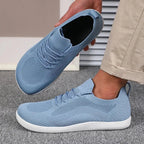 Light blue knit sneaker held in hand showing soft inner lining and white sole underside