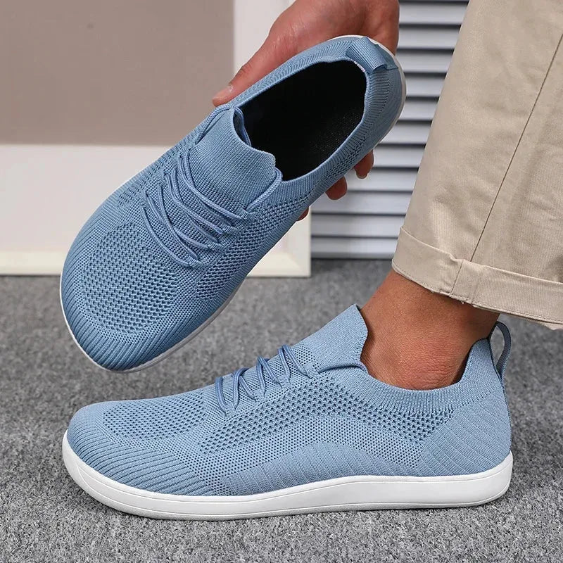 Light blue knit sneaker held in hand showing soft inner lining and white sole underside