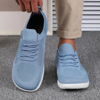 Pair of light blue knit sneakers worn on feet, one shoe pulled slightly off at heel