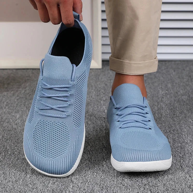 Pair of light blue knit sneakers worn on feet, one shoe pulled slightly off at heel