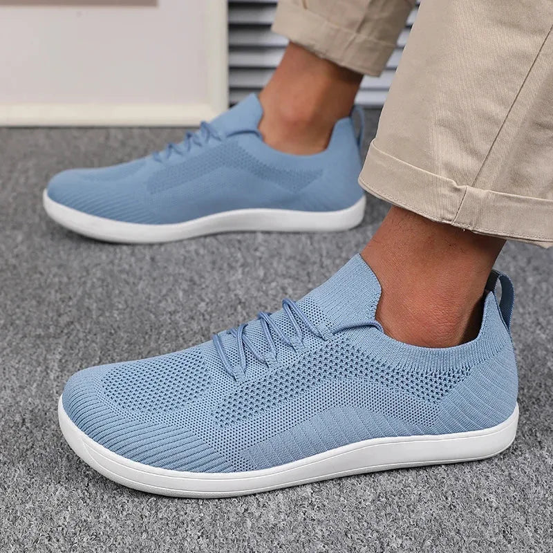 Side profile of light blue knit sneaker on foot, showing elastic lace loops and knit panels