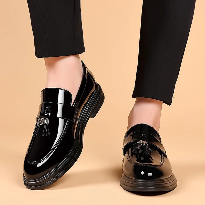 Front view of both shoes worn with cropped black trousers, showing the slip-on fit and glossy rounded toe cap.