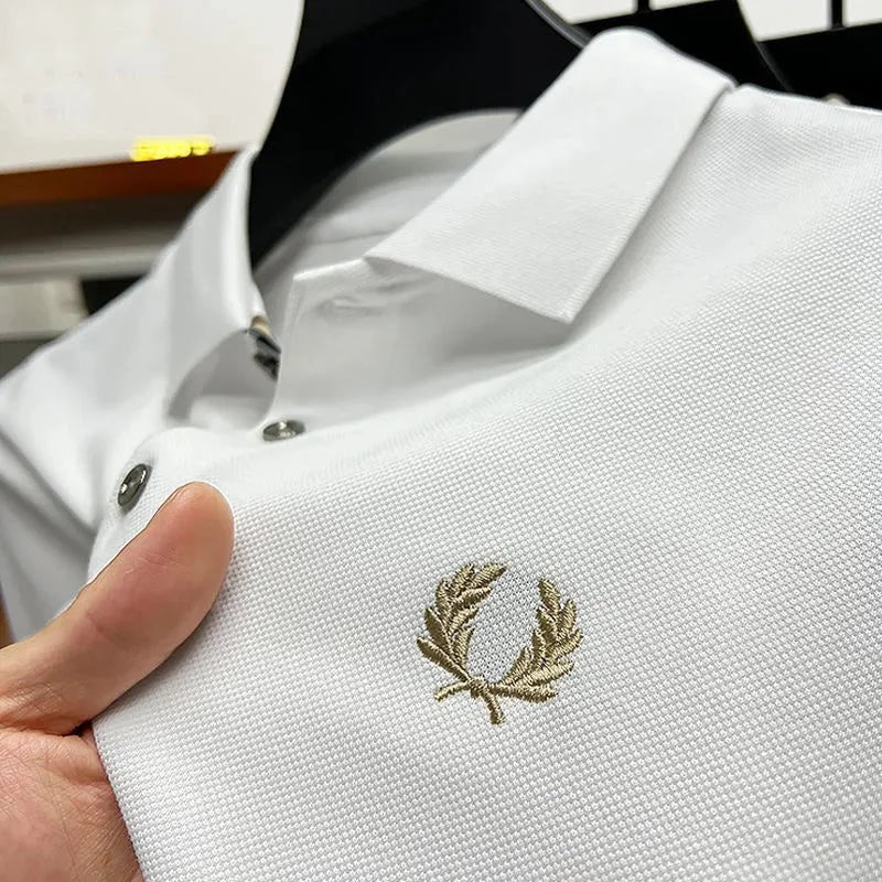 Close-up of white pique polo fabric with gold laurel wreath embroidery and contrast buttons on hanger