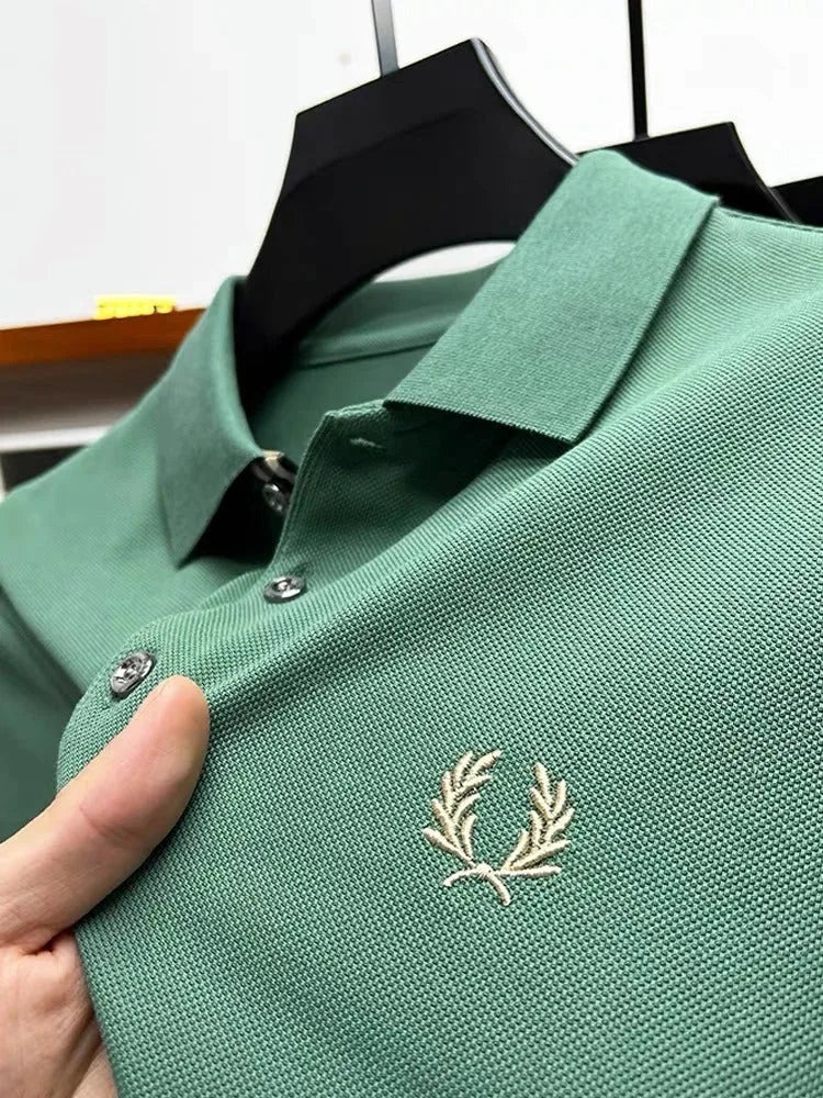 Close-up of sage green pique polo with cream laurel wreath embroidery and matching collar