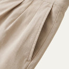 Close-up of the pleated front and side pocket detail on the beige chino shorts fabric
