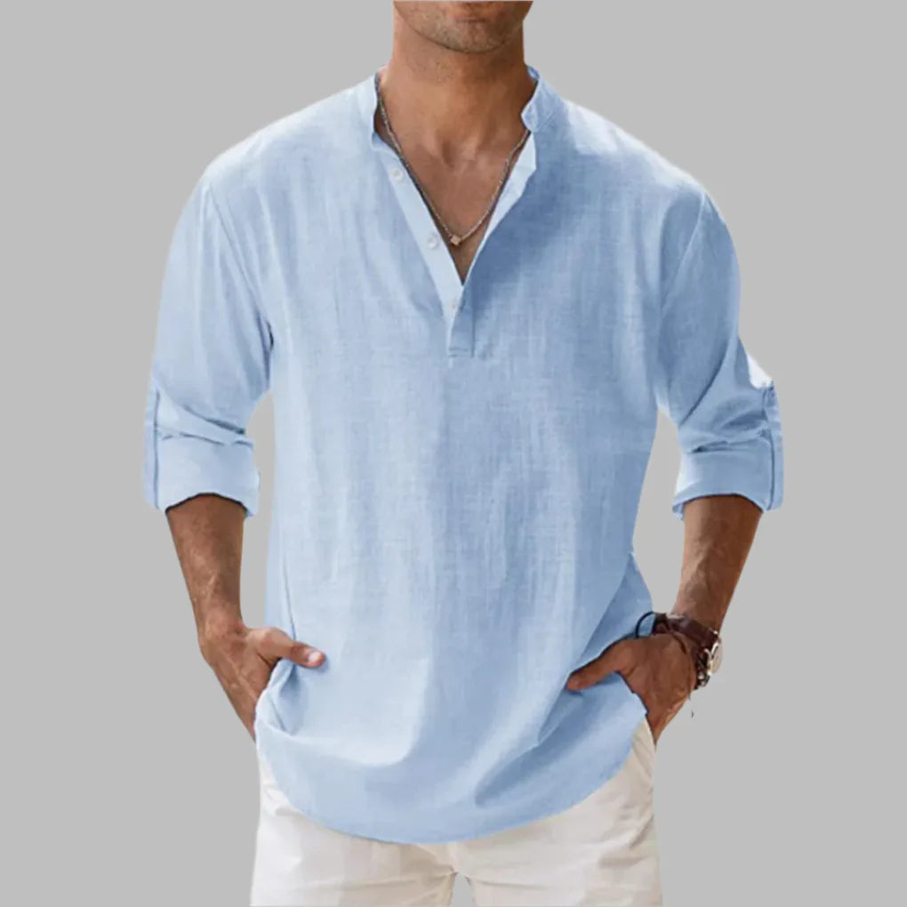 Man wearing a light blue linen shirt with buttoned notch collar, long sleeves and relaxed fit, hands in pockets