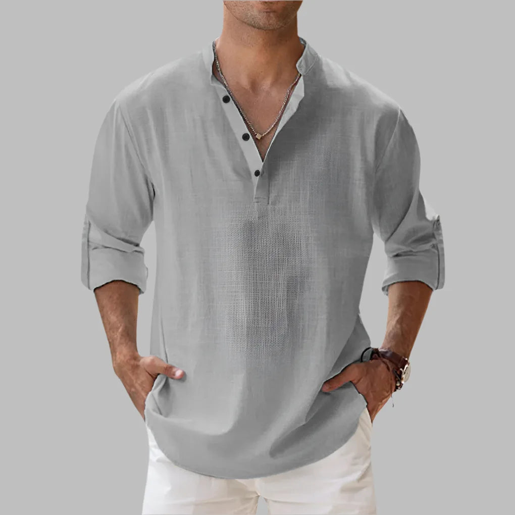 Grey textured linen shirt with button-front collar worn open at the neck, sleeves casually rolled
