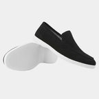 Pair of grey suede loafers arranged together, one upright and one resting on its white sole