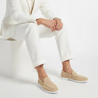 Full side view of a navy suede loafer standing upright against a plain studio background