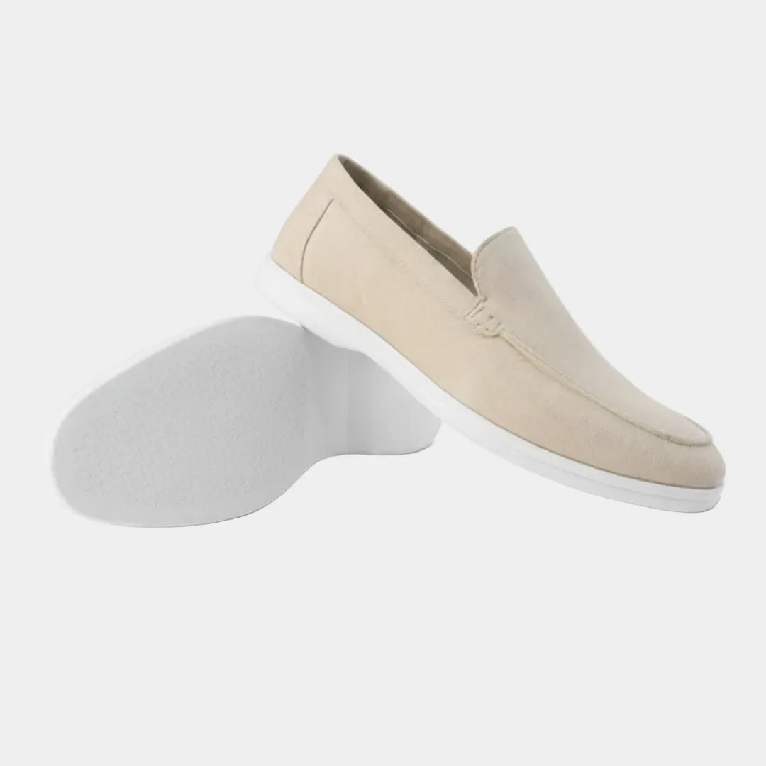 Beige suede loafer shown from the side with its matching shoe tipped to reveal a white rubber sole