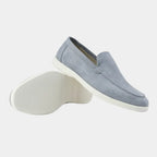 Grey suede loafer photographed side-on, resting against its pair to show the white outsole tread