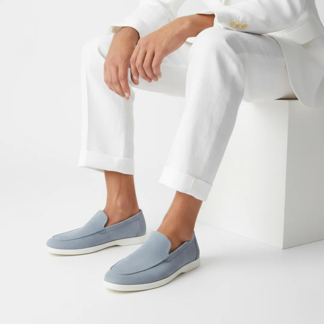 Model seated in a white linen suit wearing dusty blue suede loafers with white soles