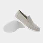 Close side view of a navy suede loafer showing the moc-toe stitching and low-profile white sole