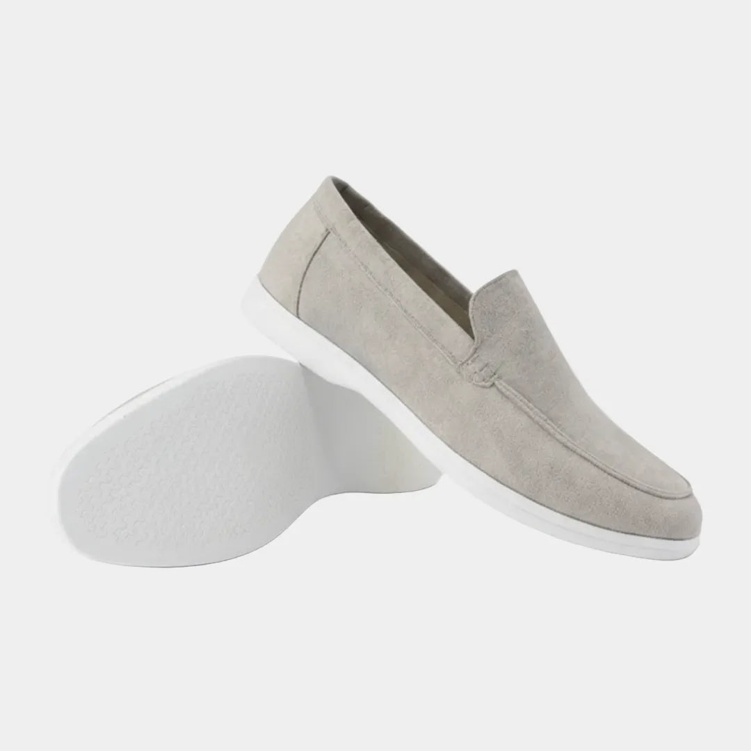 Close side view of a navy suede loafer showing the moc-toe stitching and low-profile white sole