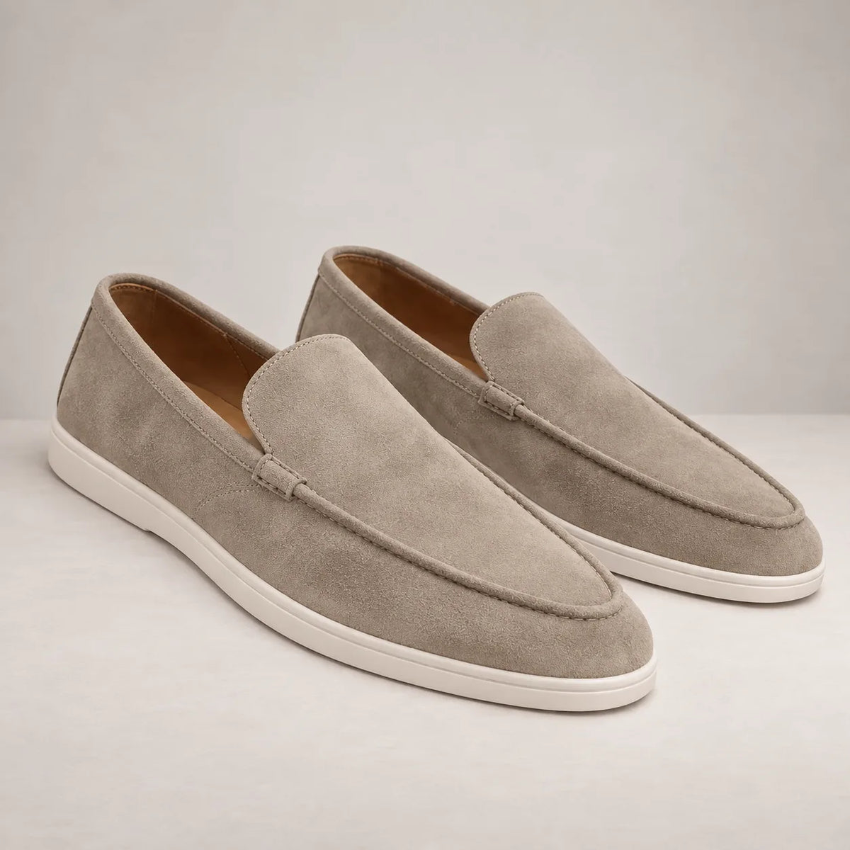 Close-up of dark brown suede loafer showing stitched toe seam and tonal knot detail