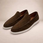 Pair of dark brown suede loafers with white sole shown at an angle on neutral background