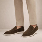 Model wearing dark brown suede loafers with white sole, paired with light beige tailored trousers