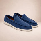 Pair of navy blue suede loafers with white sole shown at an angle on neutral background