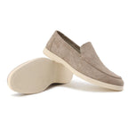 Beige suede loafers displayed side by side with one shoe tipped to show the textured sole tread