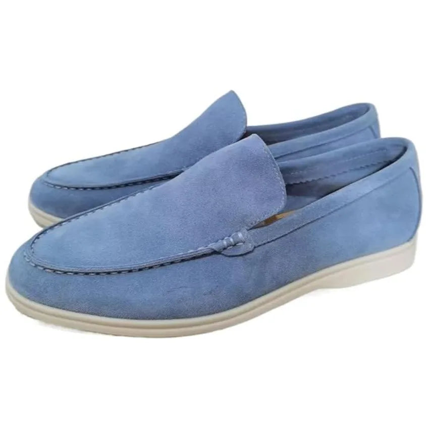 Close-up pair of light blue suede loafers with white sole on plain white background