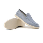 Pair of light blue suede loafers shown on their sides with the cream sole and tread pattern visible
