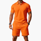 Bright orange short-sleeve polo and matching shorts set shown on a model, highlighting the relaxed fit.