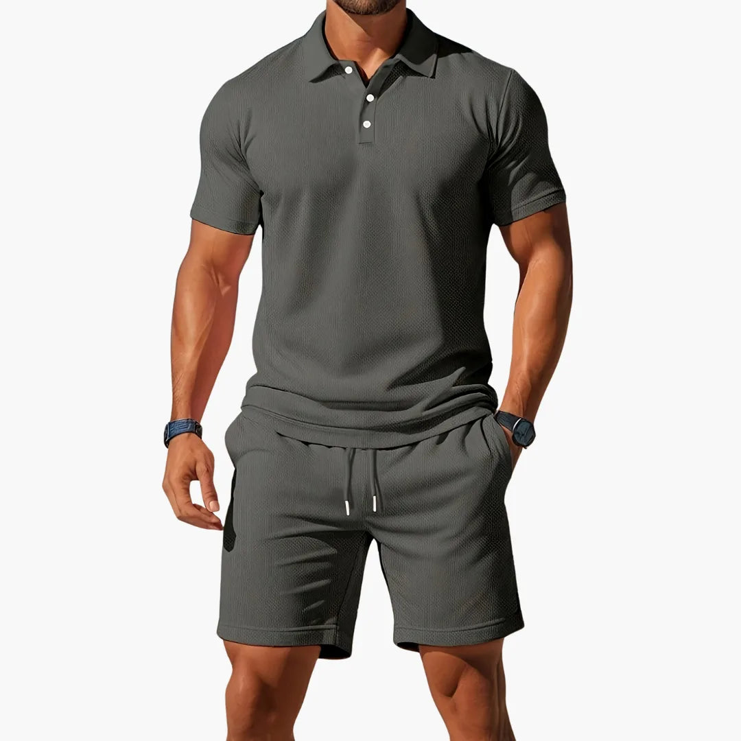 Dark grey textured polo shirt with tonal collar and matching shorts, drawstring detail visible at waist.