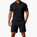 Black ribbed polo shirt and matching shorts set, close view of the button collar and relaxed sleeve fit.