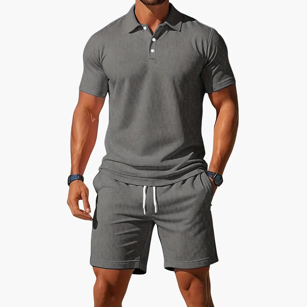Charcoal grey polo and shorts set with subtle woven texture, pocket and drawstring details visible.