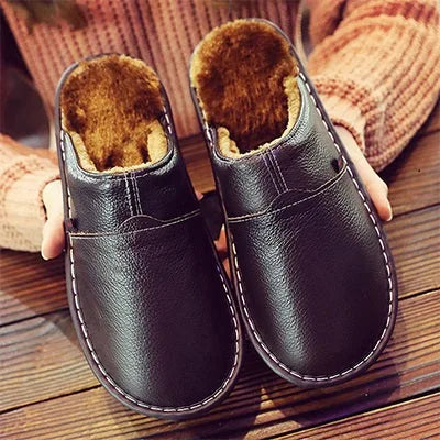 Black leather slipper with plush brown fleece lining and stitched trim, held above a wooden floor.