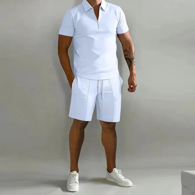White zip-neck polo shirt and matching shorts set styled with white sneakers, standing front view