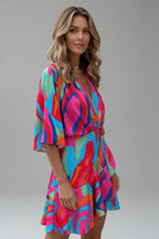Side view of a model wearing a multicoloured swirl print wrap dress showing the tie waist detail