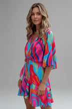 Side profile of a model in a multicoloured abstract print mini dress highlighting the flared sleeve