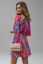 Close side view of the multicoloured wrap dress showing the ruffled asymmetric hemline